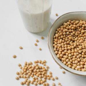 Soybeans in a bowl with a glass of soy milk on a white background.