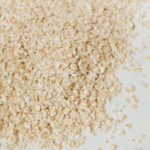 Close-up of raw oats scattered on a white surface, highlighting texture.